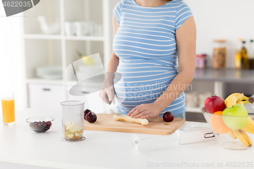 Image of pregnant woman chopping fruits at home kitchen