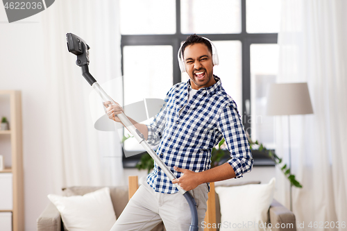 Image of man in headphones with vacuum cleaner at home