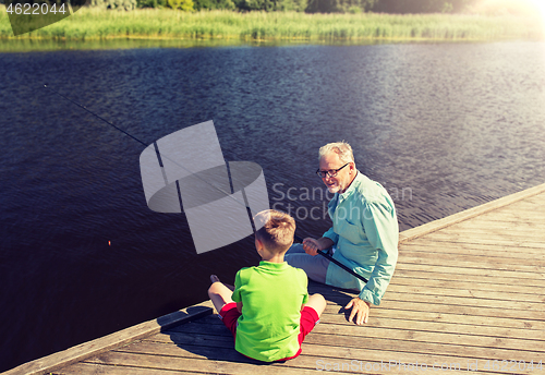 Image of grandfather and grandson fishing on river berth