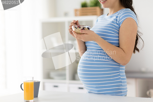Image of pregnant woman eating fruit muesli at home