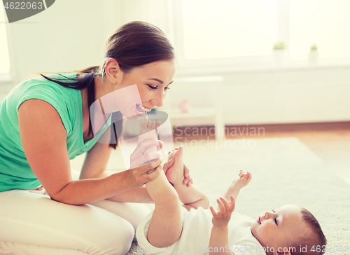 Image of happy mother playing with little baby at home