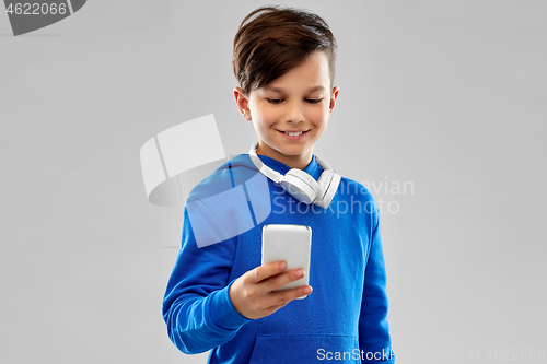 Image of smiling boy in blue hoodie using smartphone