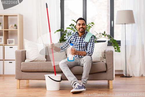 Image of indian man with mop and detergent cleaning at home