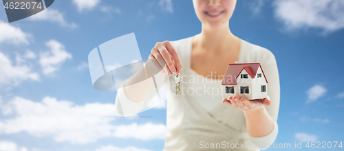 Image of close up of hands holding house model and keys