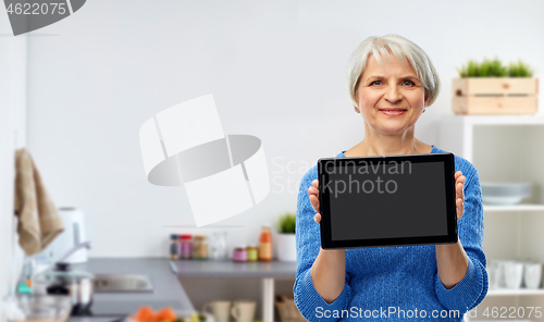 Image of senior woman using tablet computer in kitchen