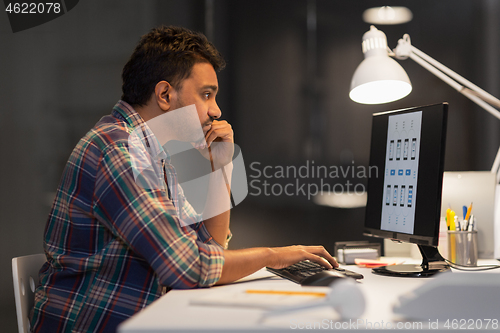 Image of creative man with computer working at night office