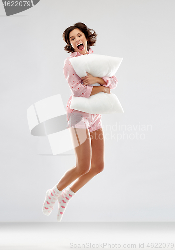 Image of happy woman in pajama jumping with pillow