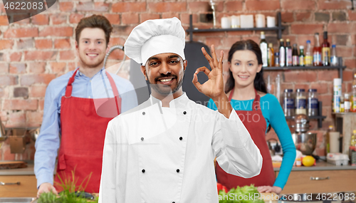 Image of happy male indian chef showing ok at cooking class