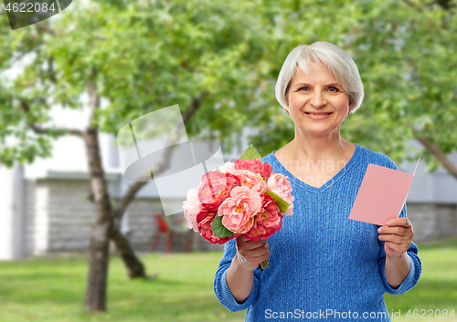 Image of happy senior woman with flowers and greeting card
