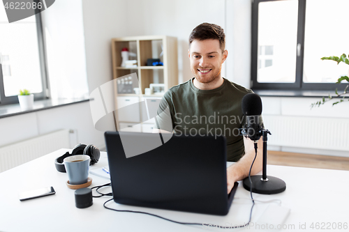 Image of man with laptop and microphone at home office