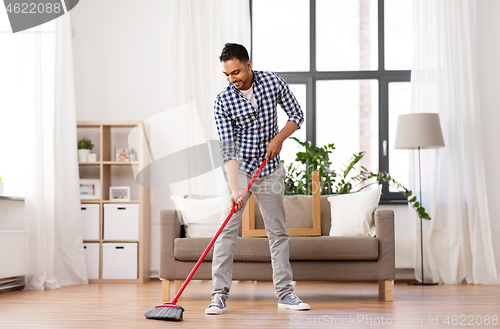 Image of man with broom cleaning floor at home