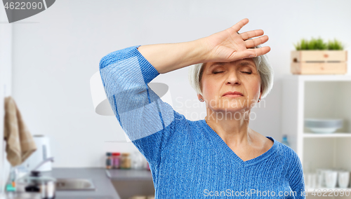 Image of tired senior woman at kitchen