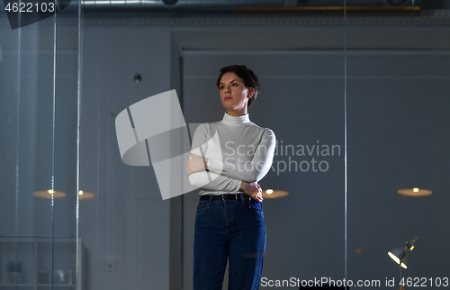 Image of businesswoman looks at glass wall at night office