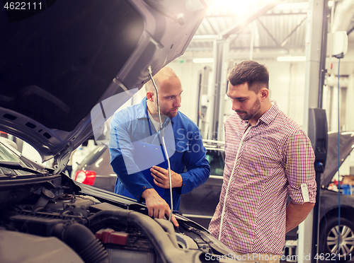 Image of auto mechanic with clipboard and man at car shop