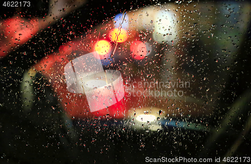 Image of The lights of the night city through the glass with raindrops