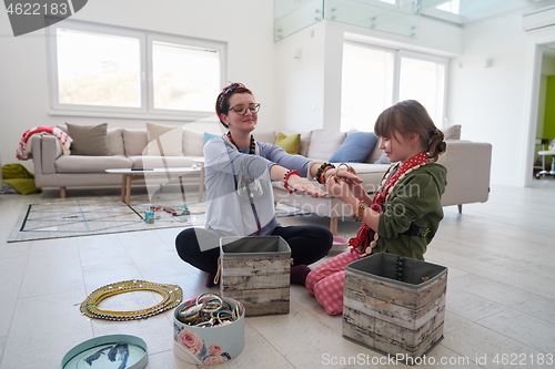 Image of Mother and little girl daughter playing with jewelry  at home