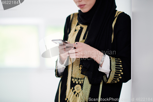 Image of young modern muslim business woman using smartphone at home