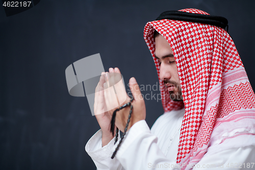 Image of arabian man making traditional prayer to God, keeps hands in pra