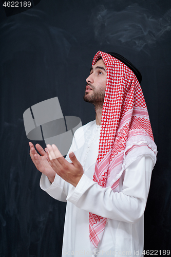 Image of arabian man making traditional prayer to God, keeps hands in pra