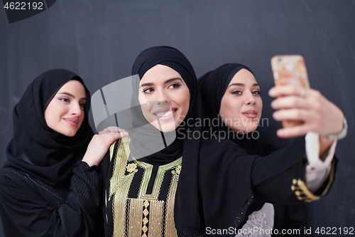 Image of muslim women taking selfie picture in front of black chalkboard