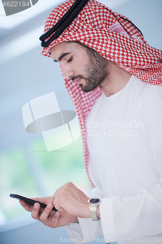 Image of young arabian businessman using smartphone at home