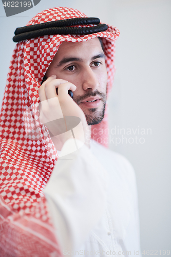 Image of young arabian businessman using smartphone at home