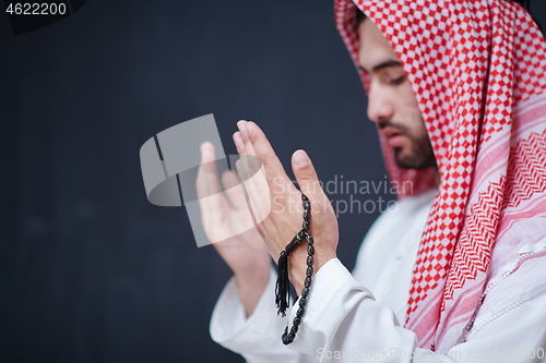 Image of arabian man making traditional prayer to God, keeps hands in pra