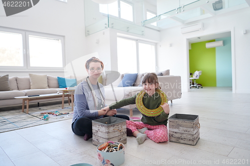 Image of Mother and little girl daughter playing with jewelry  at home