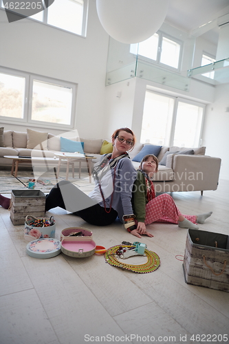 Image of Mother and little girl daughter playing with jewelry  at home