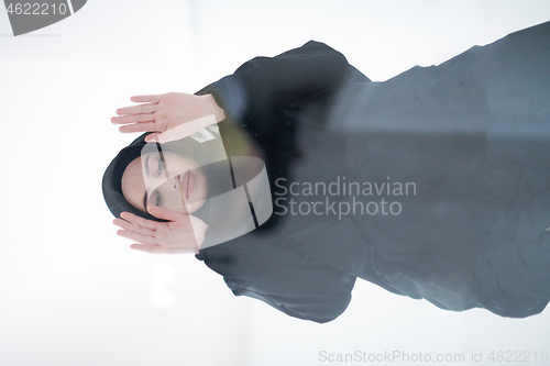 Image of young arabian muslim woman praying on the glass floor at home