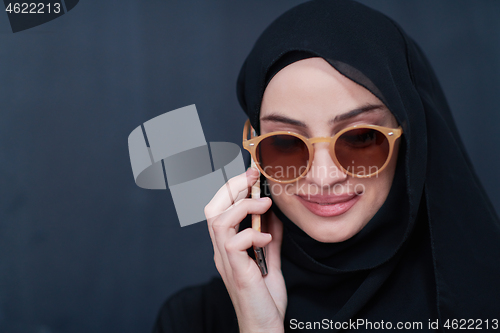 Image of young muslim woman wearing sunglasses using smartphone