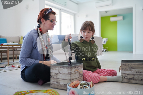 Image of Mother and little girl daughter playing with jewelry  at home