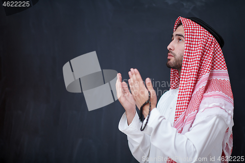 Image of arabian man making traditional prayer to God, keeps hands in pra