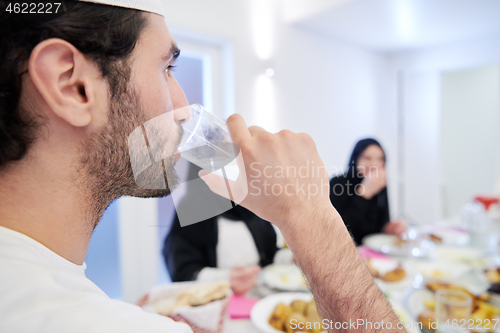 Image of Muslim family having Iftar dinner drinking water to break feast