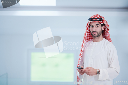 Image of young arabian businessman using smartphone at home