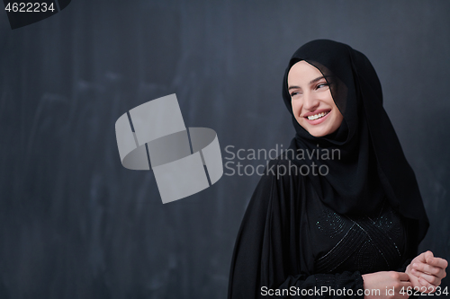 Image of portrait of beautiful muslim woman in front of black chalkboard