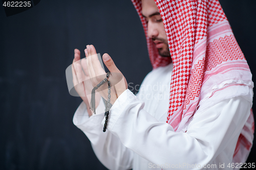 Image of arabian man making traditional prayer to God, keeps hands in pra