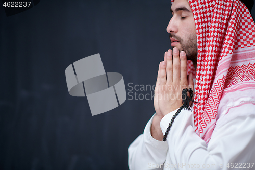 Image of arabian man making traditional prayer to God, keeps hands in pra