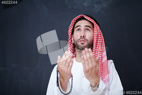 Image of arabian man making traditional prayer to God, keeps hands in pra