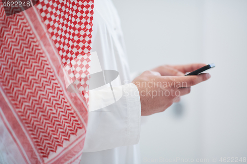 Image of young arabian businessman using smartphone at home