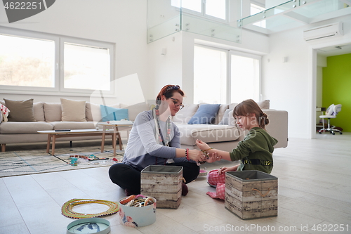 Image of Mother and little girl daughter playing with jewelry  at home