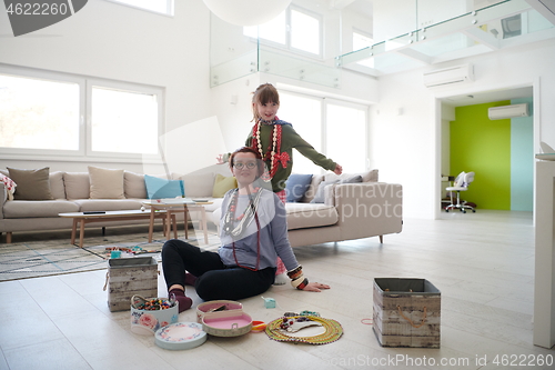 Image of Mother and little girl daughter playing with jewelry  at home