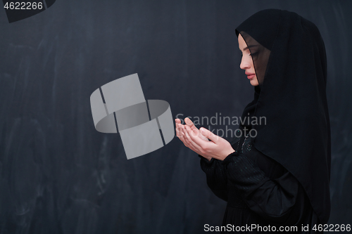 Image of muslim woman making traditional prayer to God in front of black 