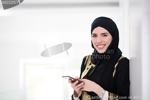 Image of young modern muslim business woman using smartphone at home