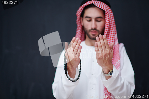 Image of arabian man making traditional prayer to God, keeps hands in pra