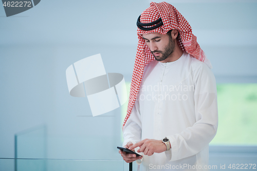 Image of young arabian businessman using smartphone at home