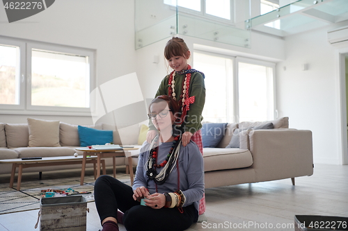 Image of Mother and little girl daughter playing with jewelry  at home