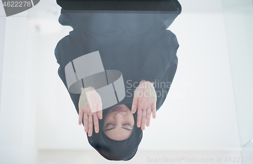 Image of young arabian muslim woman praying on the glass floor at home