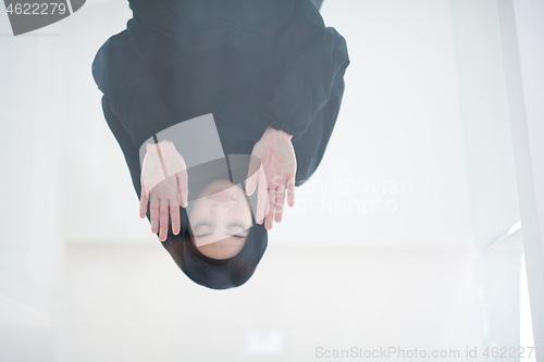 Image of young arabian muslim woman praying on the glass floor at home