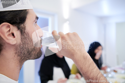 Image of Muslim family having Iftar dinner drinking water to break feast